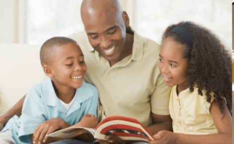 Father reading book to smiling children