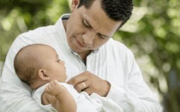 Father holding baby outdoors, tender moment