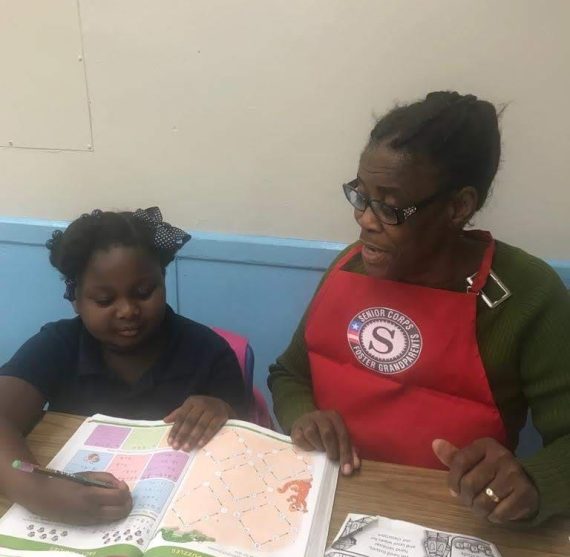Woman tutoring child with workbook at table